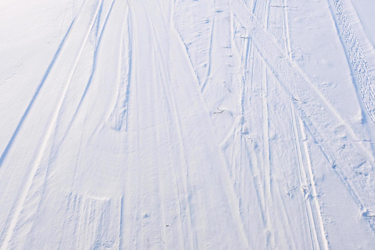 skidspår i den vita och blå snön på bergsytan foto