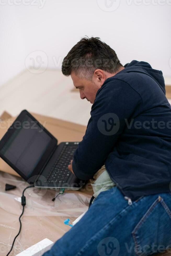 man använder sig av bärbar dator medan liggande på kartong låda foto