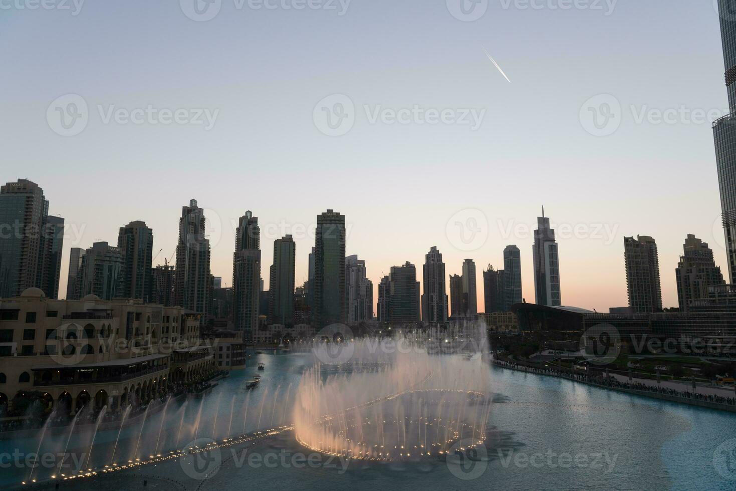 dubai sång fontäner på natt sjö se mellan skyskrapor. stad horisont i skymning modern arkitektur i uae huvudstad stadens centrum. foto