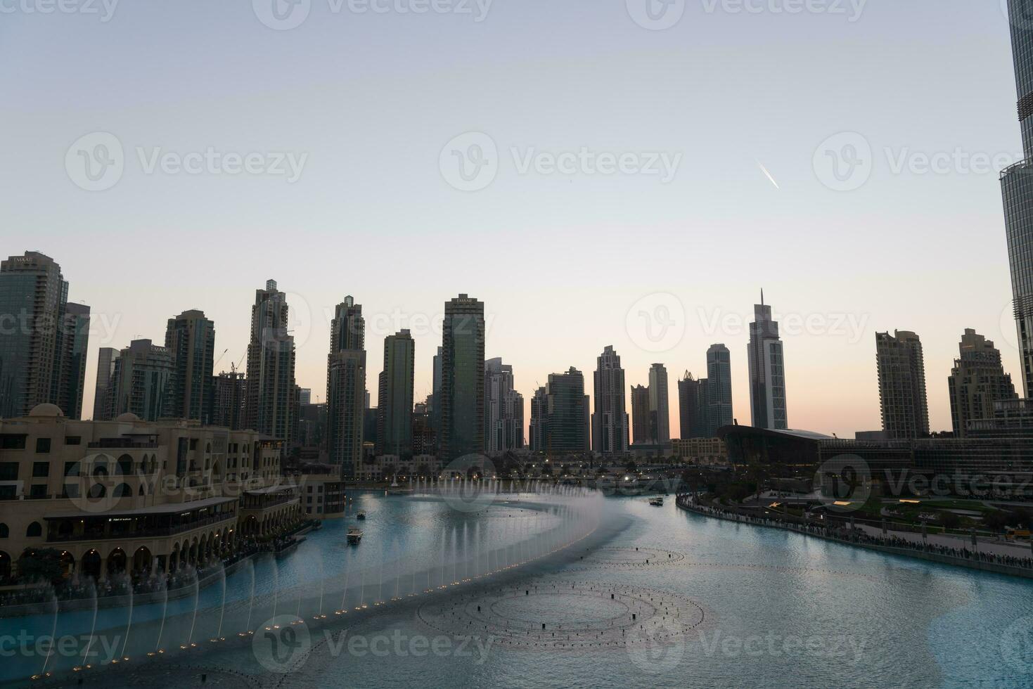 dubai sång fontäner på natt sjö se mellan skyskrapor. stad horisont i skymning modern arkitektur i uae huvudstad stadens centrum. foto