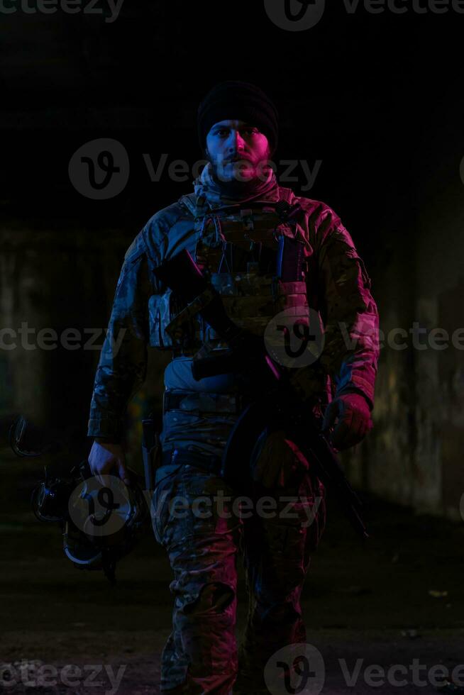 armén soldat i bekämpa uniformer med ett överfall gevär och bekämpa hjälm natt uppdrag mörk bakgrund. blå och lila gel ljus effekt. foto