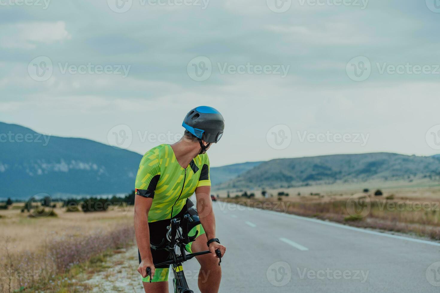 stänga upp Foto av ett aktiva triathlete i sportkläder och med en skyddande hjälm ridning en cykel. selektiv fokus