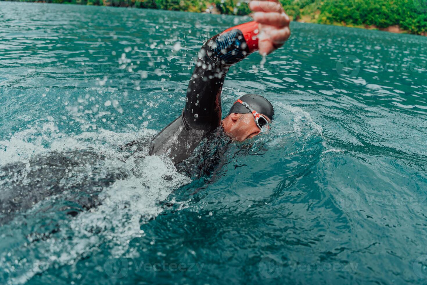 en triathlete i en professionell simning kostym tåg på de flod medan framställning för olympic simning foto