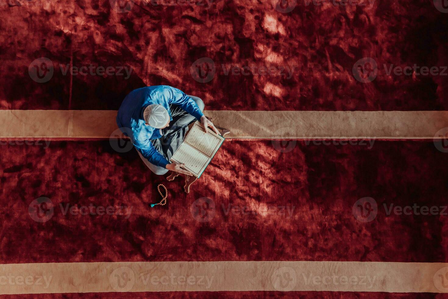 en muslim läser de helig islamic bok quraqn i en modern stor moské under de muslim helig månad av ranazan foto