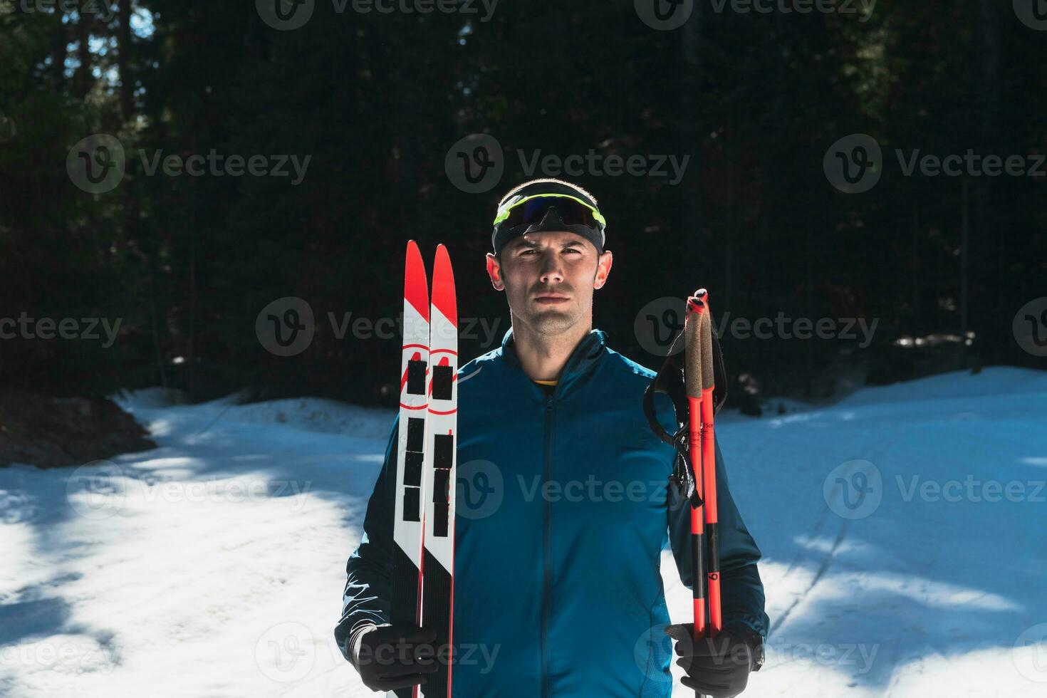 porträtt stilig manlig idrottare med korsa Land skidor i händer och glasögon, Träning i snöig skog. friska vinter- livsstil begrepp. foto
