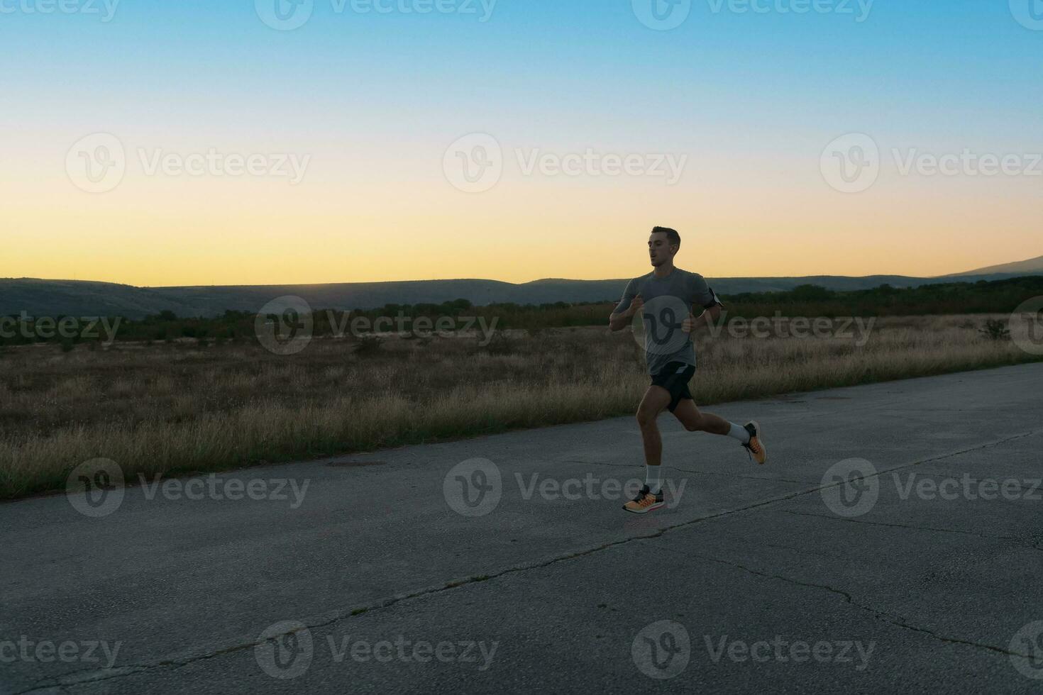 attraktiv passa man löpning snabb längs landsbygden väg på solnedgång ljus, håller på med joggning träna utomhus foto