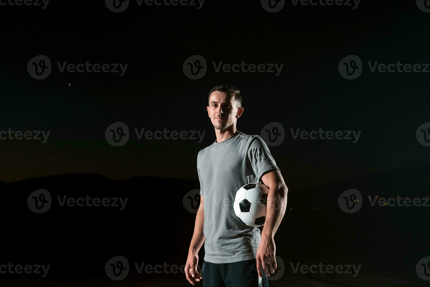 porträtt av en ung stilig fotboll spelare man på en gata spelar med en fotboll boll. foto