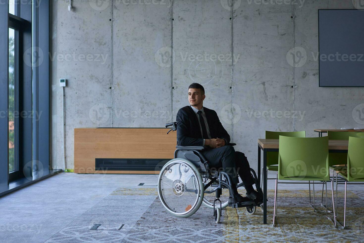 affärsman i en rullstol i en modern kontor ensam efter en upptagen dag foto