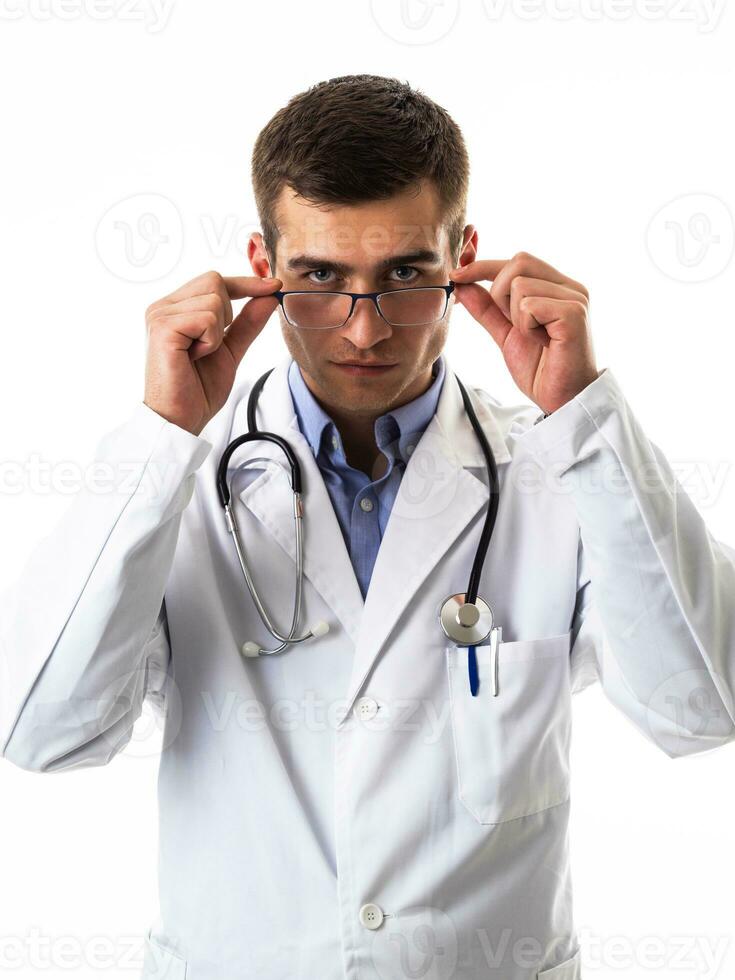 självsäker manlig läkare i vit labb täcka och stetoskop stående med vikta vapen leende på de kamera isolerat på vit foto