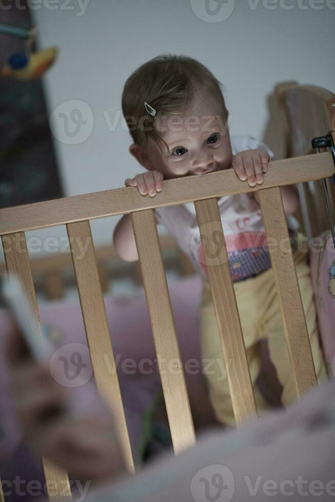 söt liten ett år gammal bebis och framställning först steg i säng foto