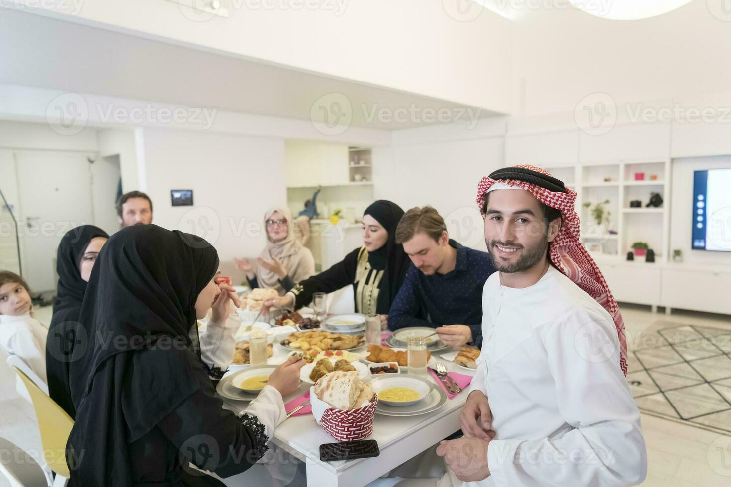 ung arab man har iftar middag med muslim familj äter traditionell mat under ramadan festande månad på Hem. de islamic halal äter och dricka islamic familj foto