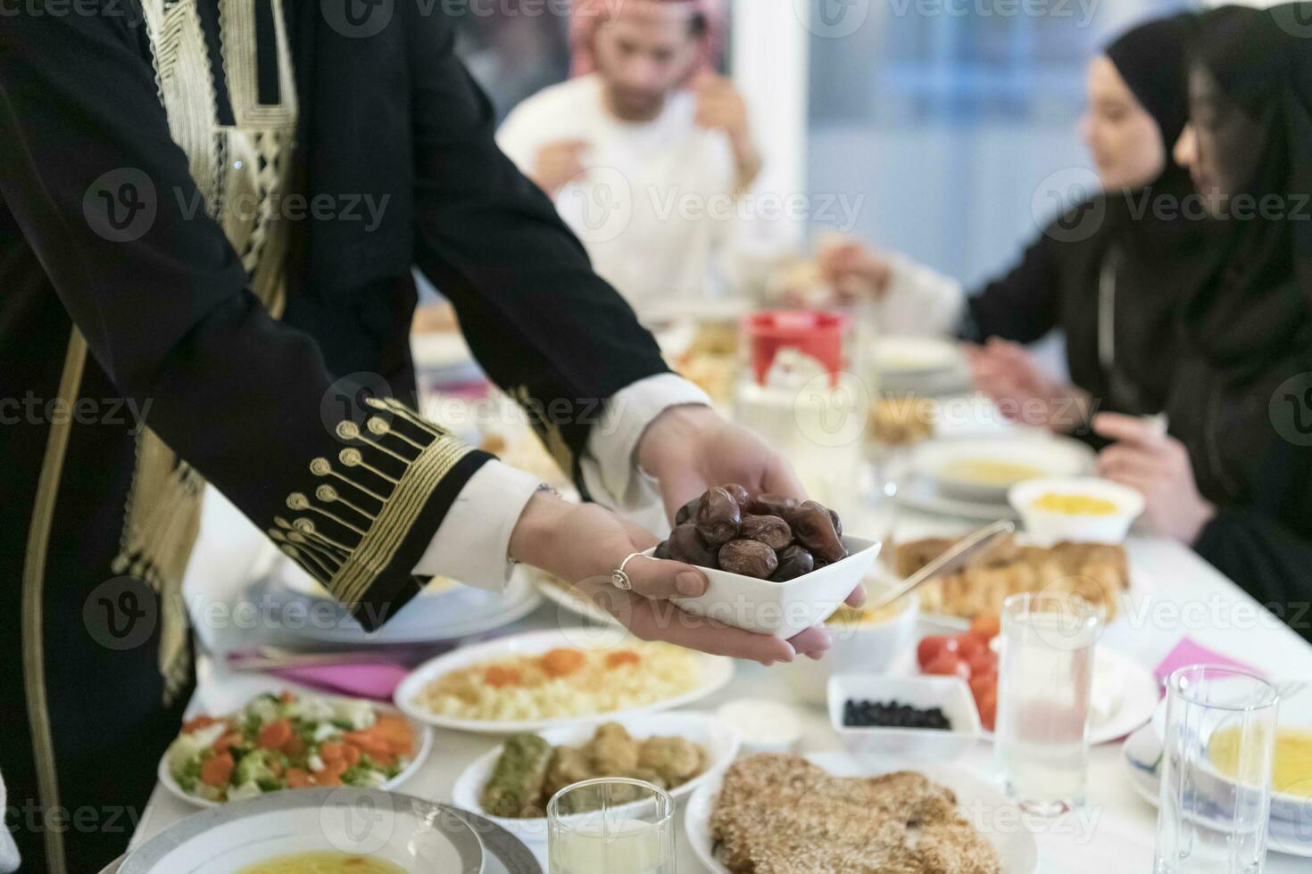 modern multietnisk muslim familj delning en skål av datum medan njuter iftar middag tillsammans under en ramadan fest på Hem foto