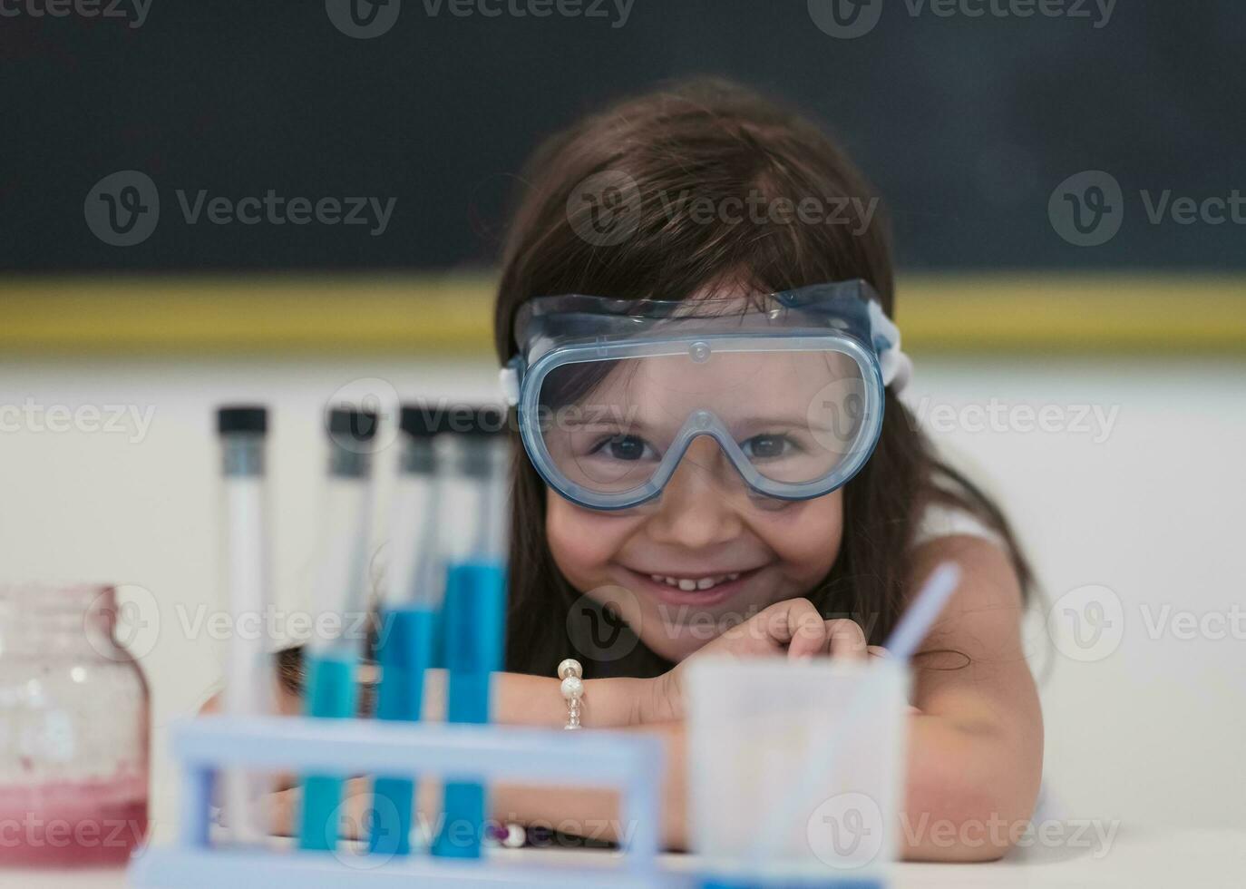 elementärt skola vetenskap klassrum liten flicka blandar kemikalier i bägare. barn lära sig med intressera foto