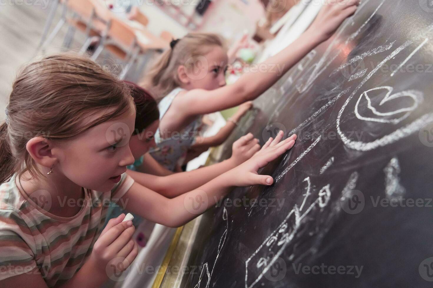 barn skriva och dra på de svarta tavlan i elementärt skola medan inlärning de grunderna av utbildning foto