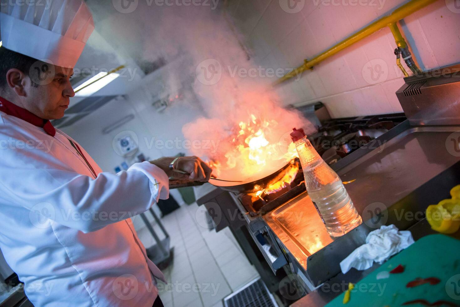 kock håller på med flambe på mat foto