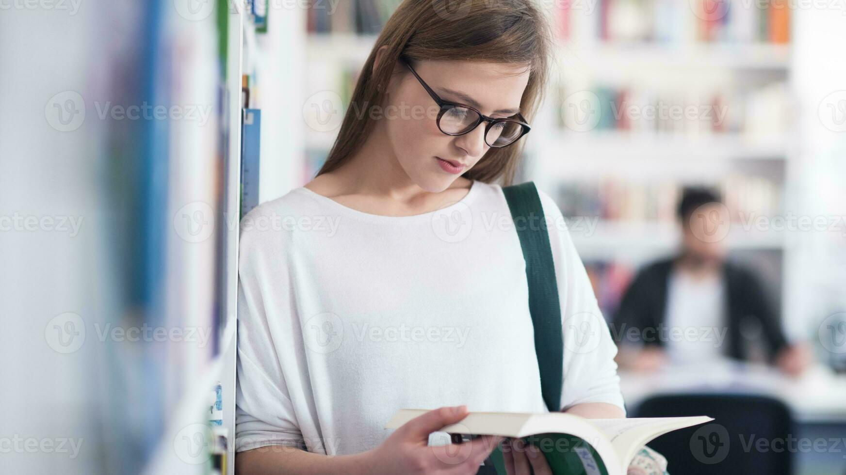 porträtt av famale studerande läsning bok i bibliotek foto