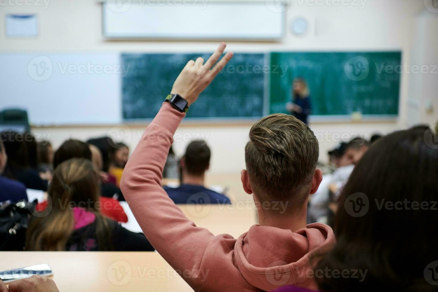 de studerande höjer hans händer be en fråga i klass i högskola foto