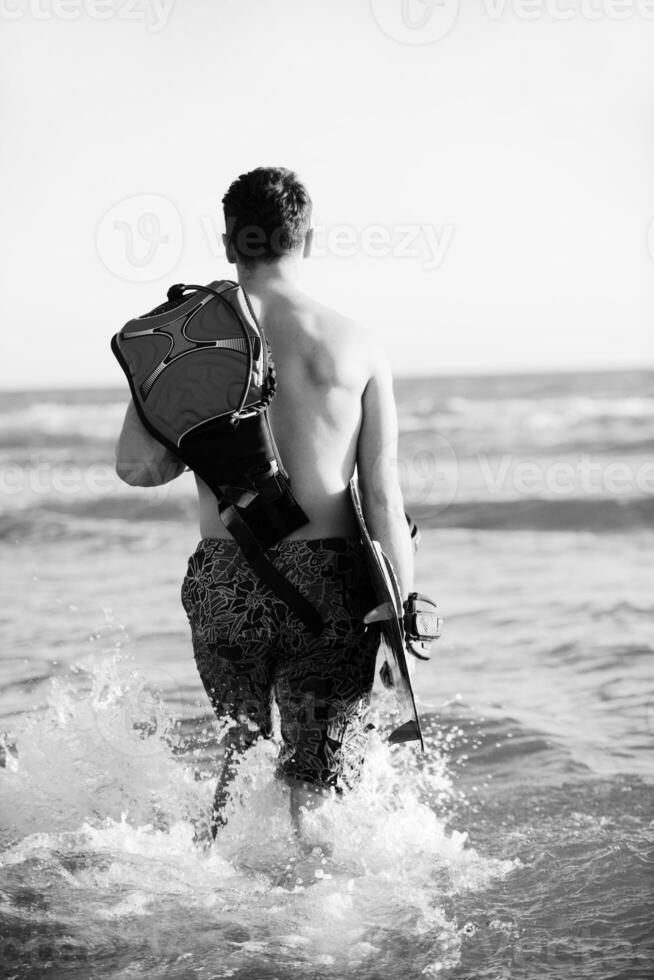 porträtt av en ung kitsurf man på strand på solnedgång foto