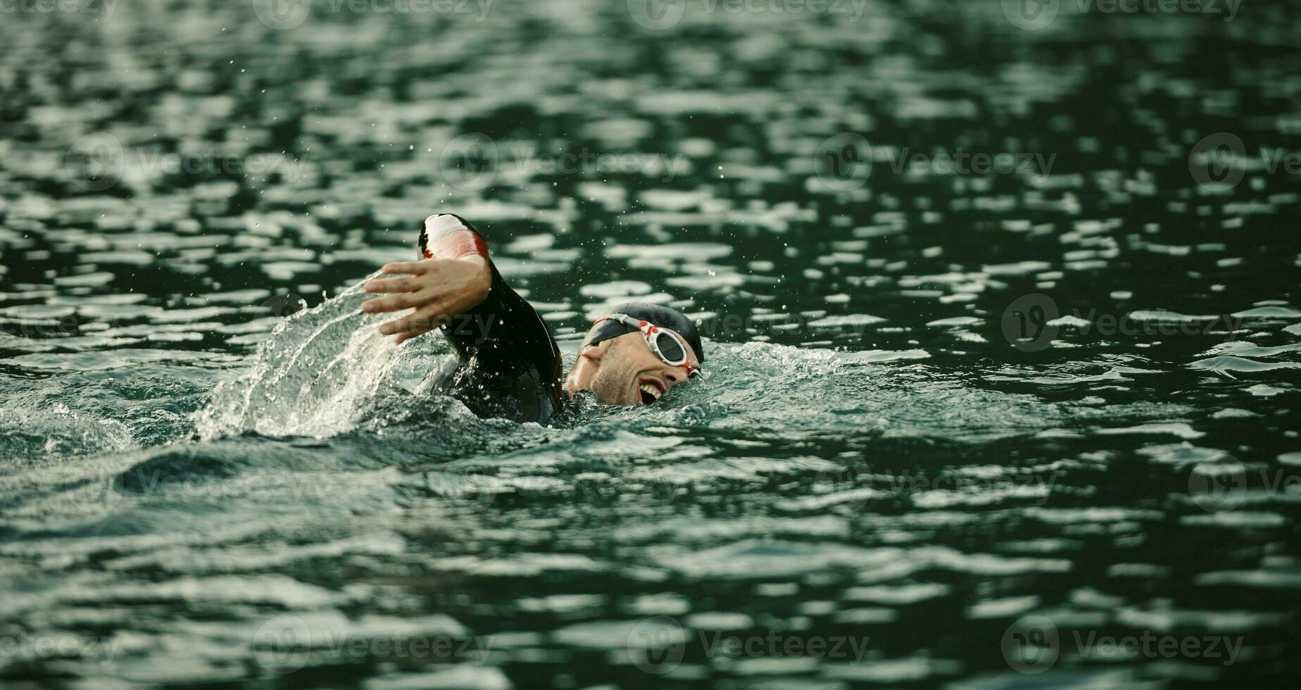 triathlon idrottare simmar på sjön i soluppgången bär våtdräkt foto