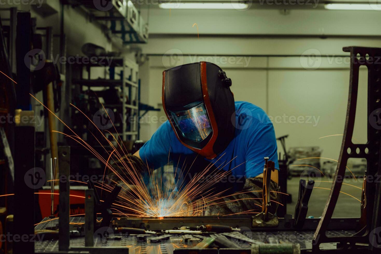 professionell tungindustrisvetsare som arbetar inne i fabriken, bär hjälm och börjar svetsa. selektiv fokusering foto