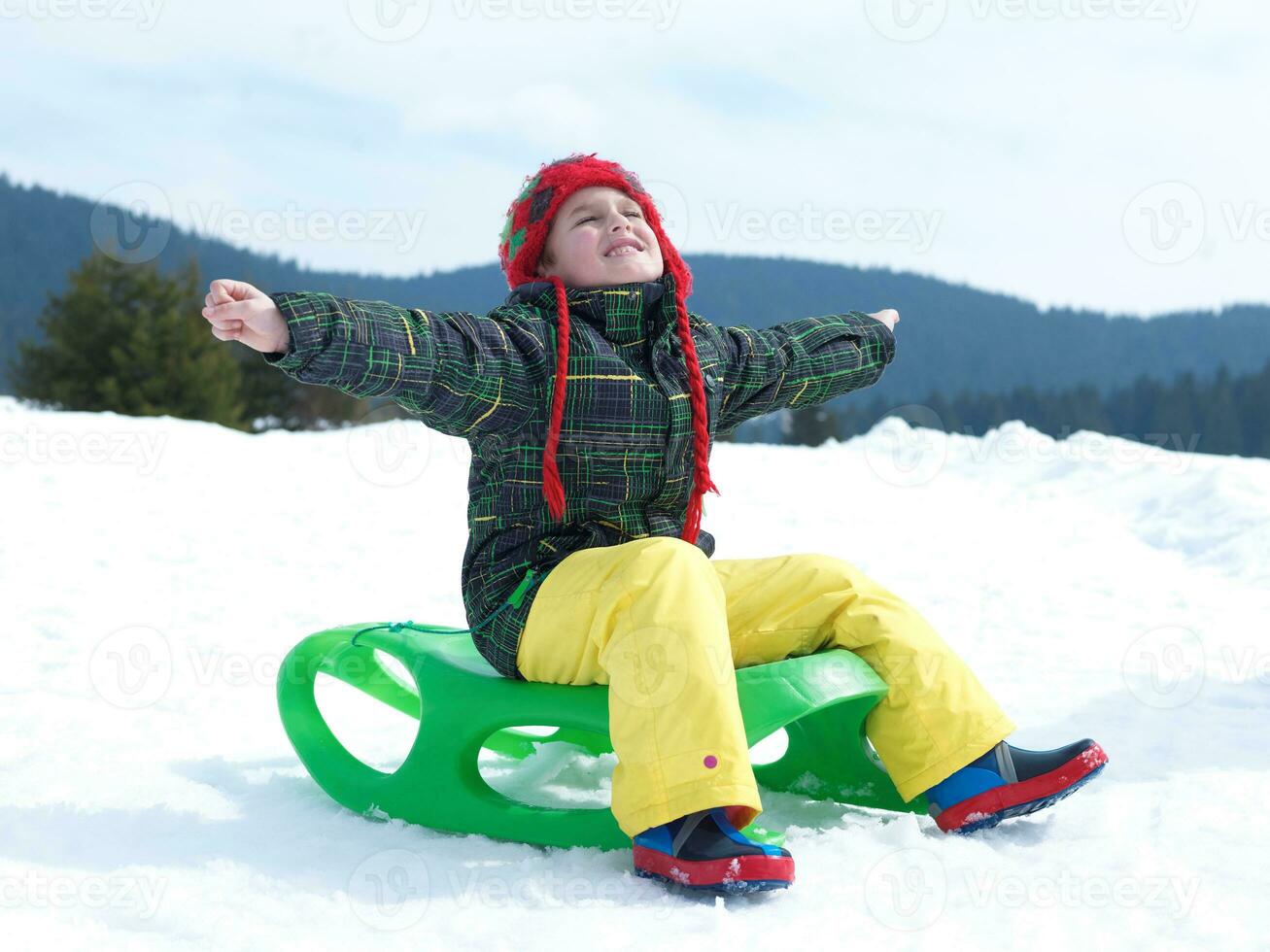 Lycklig ung pojke ha roligt på vinter- semester på färsk snö foto