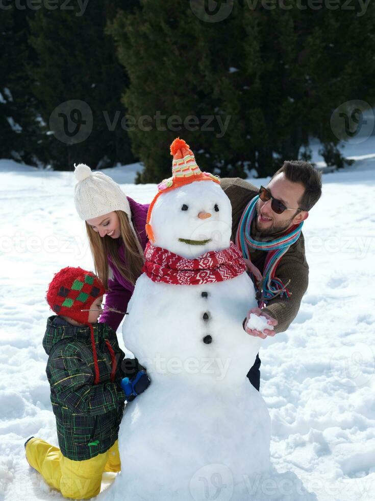 lycklig familj som gör snögubbe foto