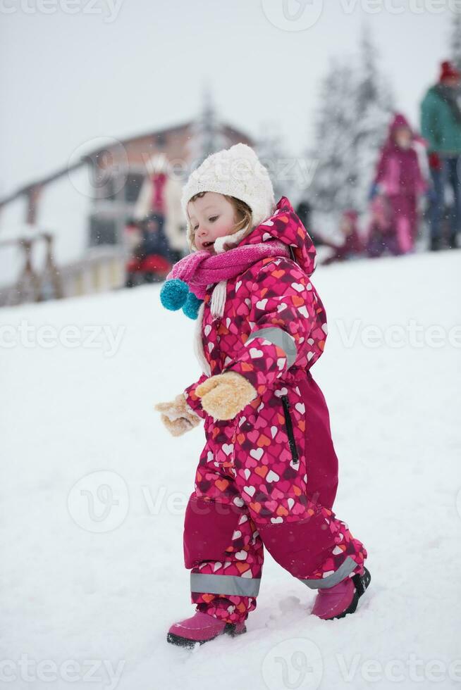 liten flicka ha roligt på snöig vinter- dag foto