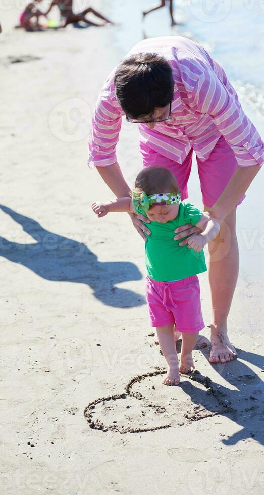 mamma och bebis på stranden har kul foto