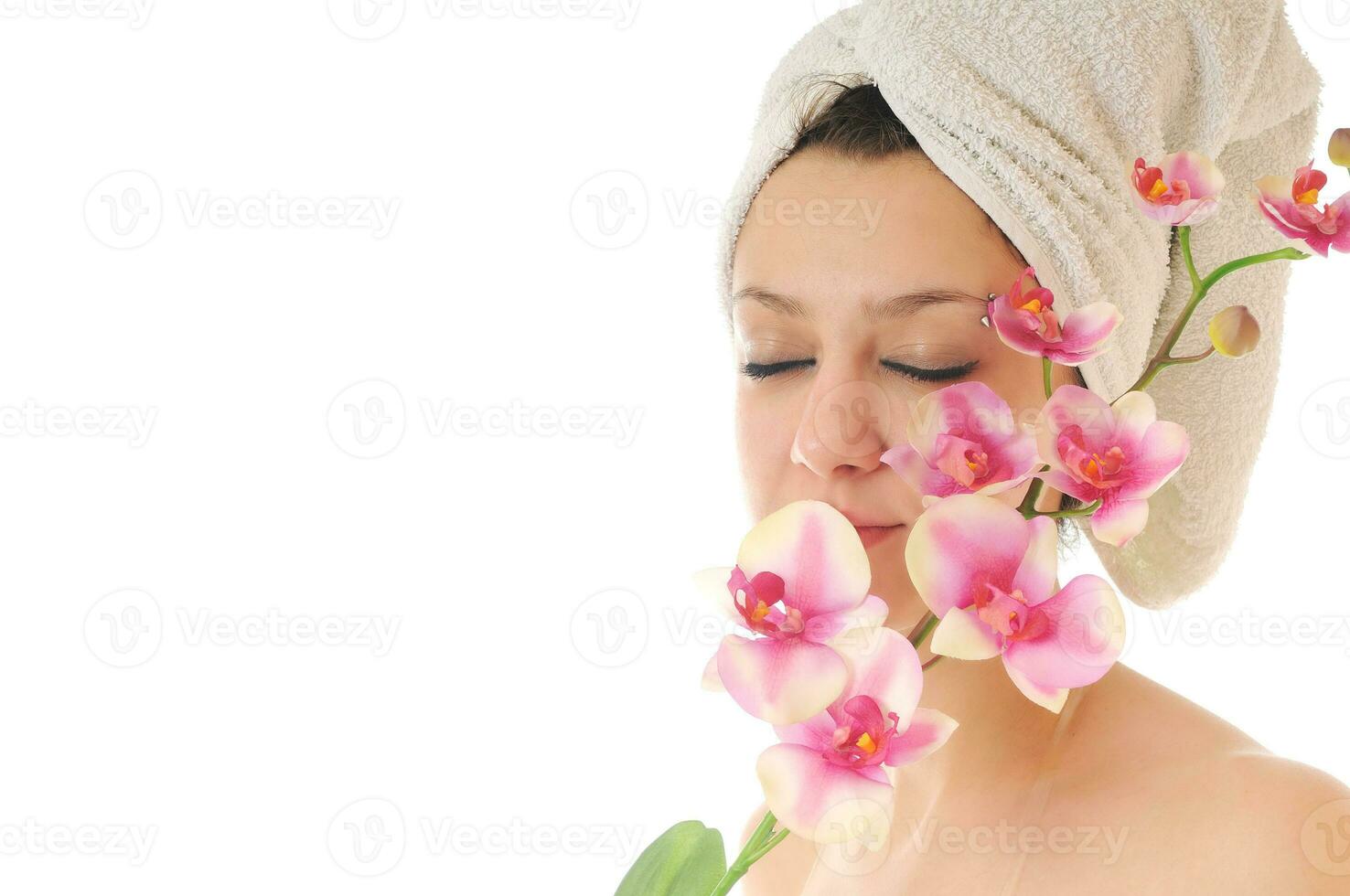 skön ung kvinna ansikte med blomma och handduk foto