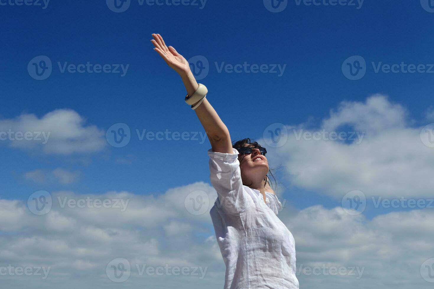 glad ung kvinna med utspridda armar mot himlen foto