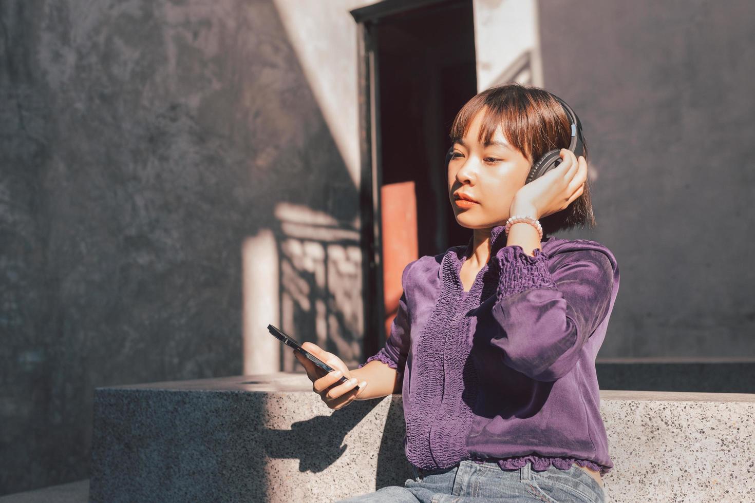 glad ung asiatisk kvinna som lyssnar på musik med hörlurar foto