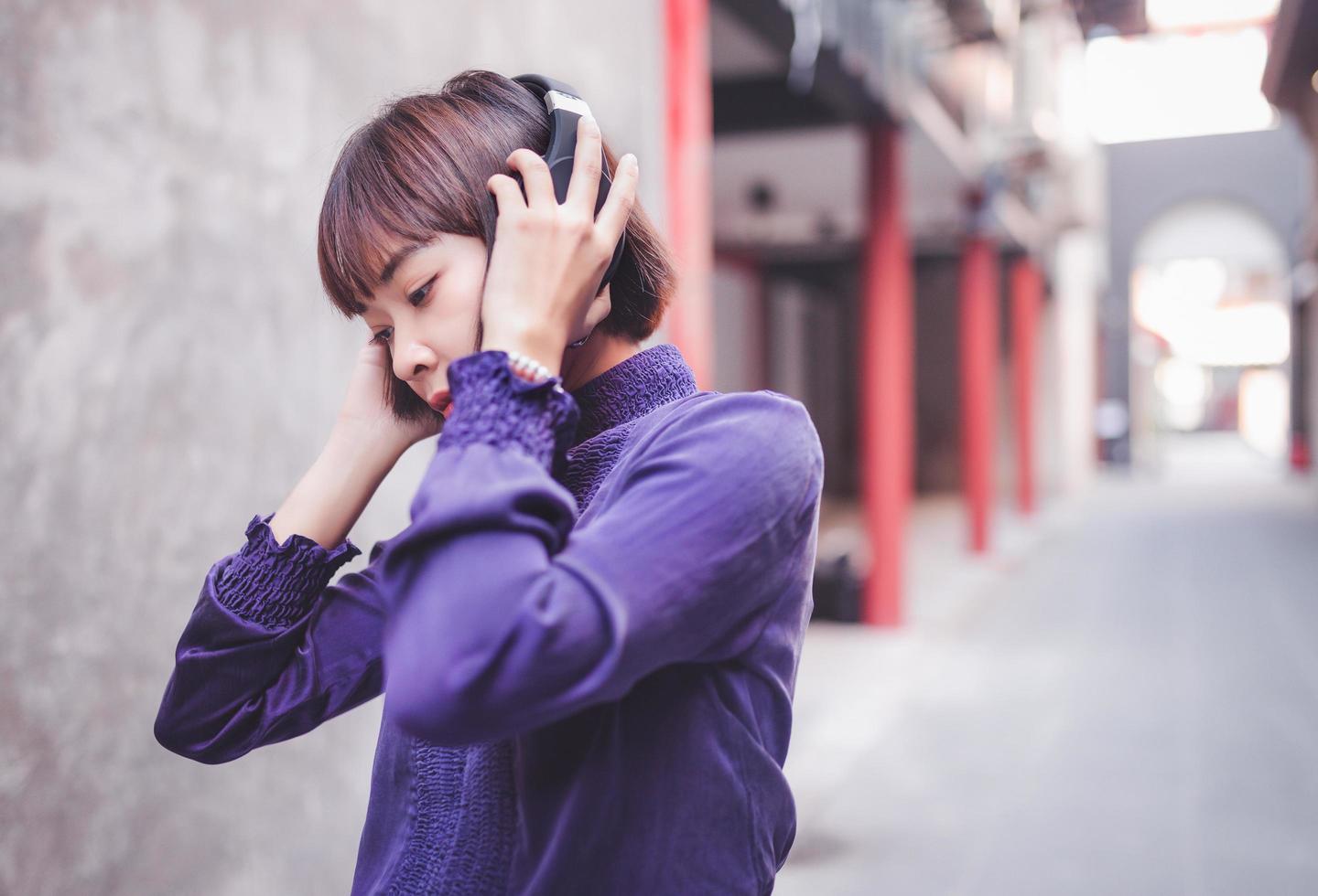 glad ung asiatisk kvinna som lyssnar på musik med hörlurar foto