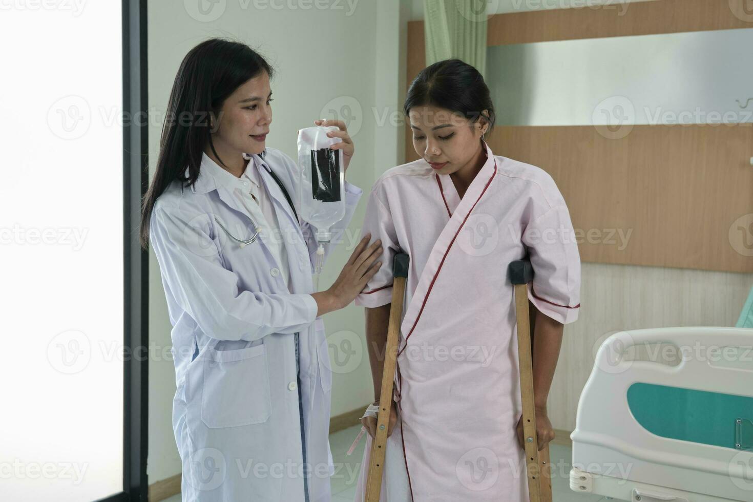 asiatisk kvinna ortopedisk läkare portion patient kvinna med salin till promenad med kryckor i en sjukhus klinik efter fysisk terapi förbi muskel medicinsk behandling återhämtning från skada. foto