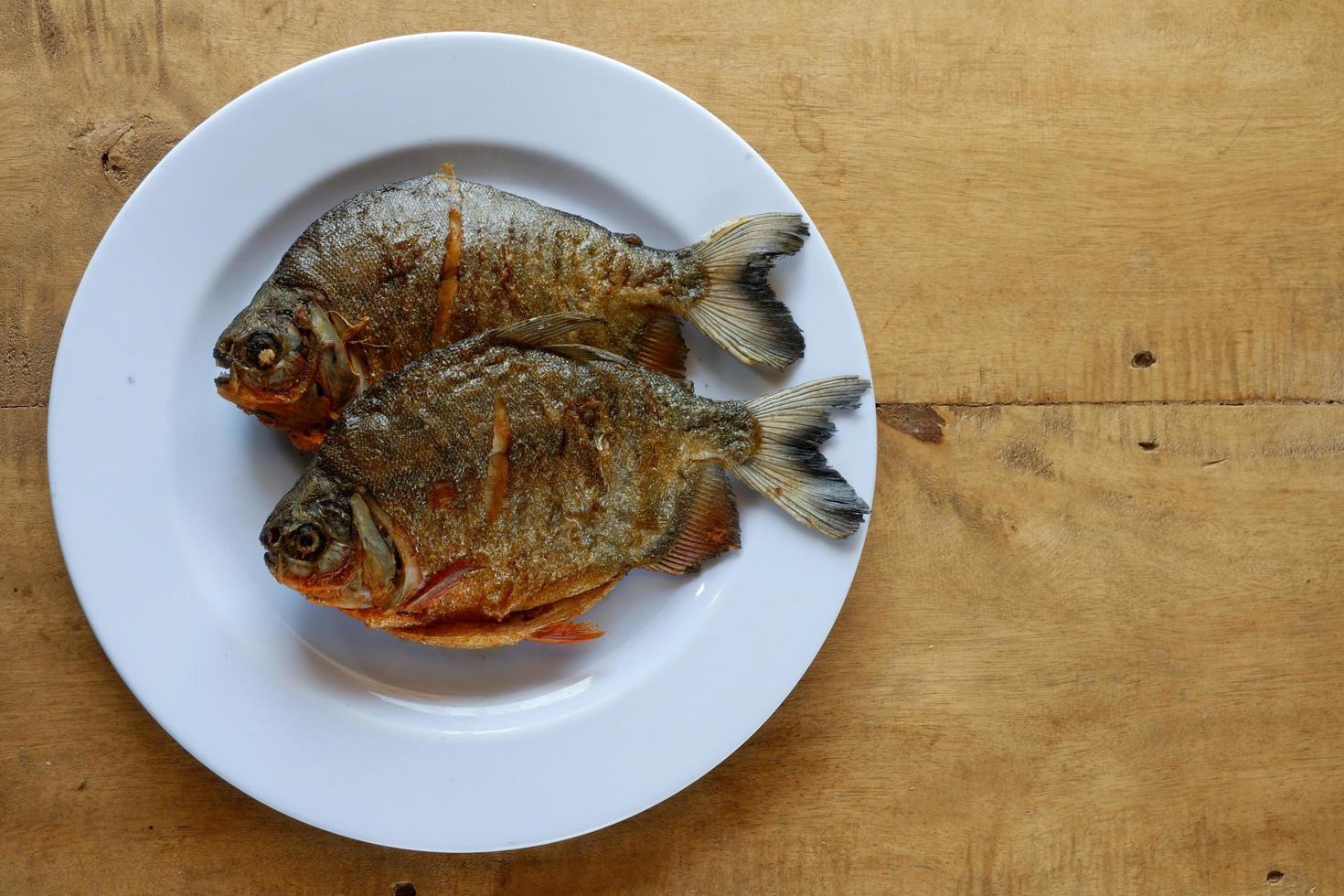 pomfret på vit tallrik med träbord foto