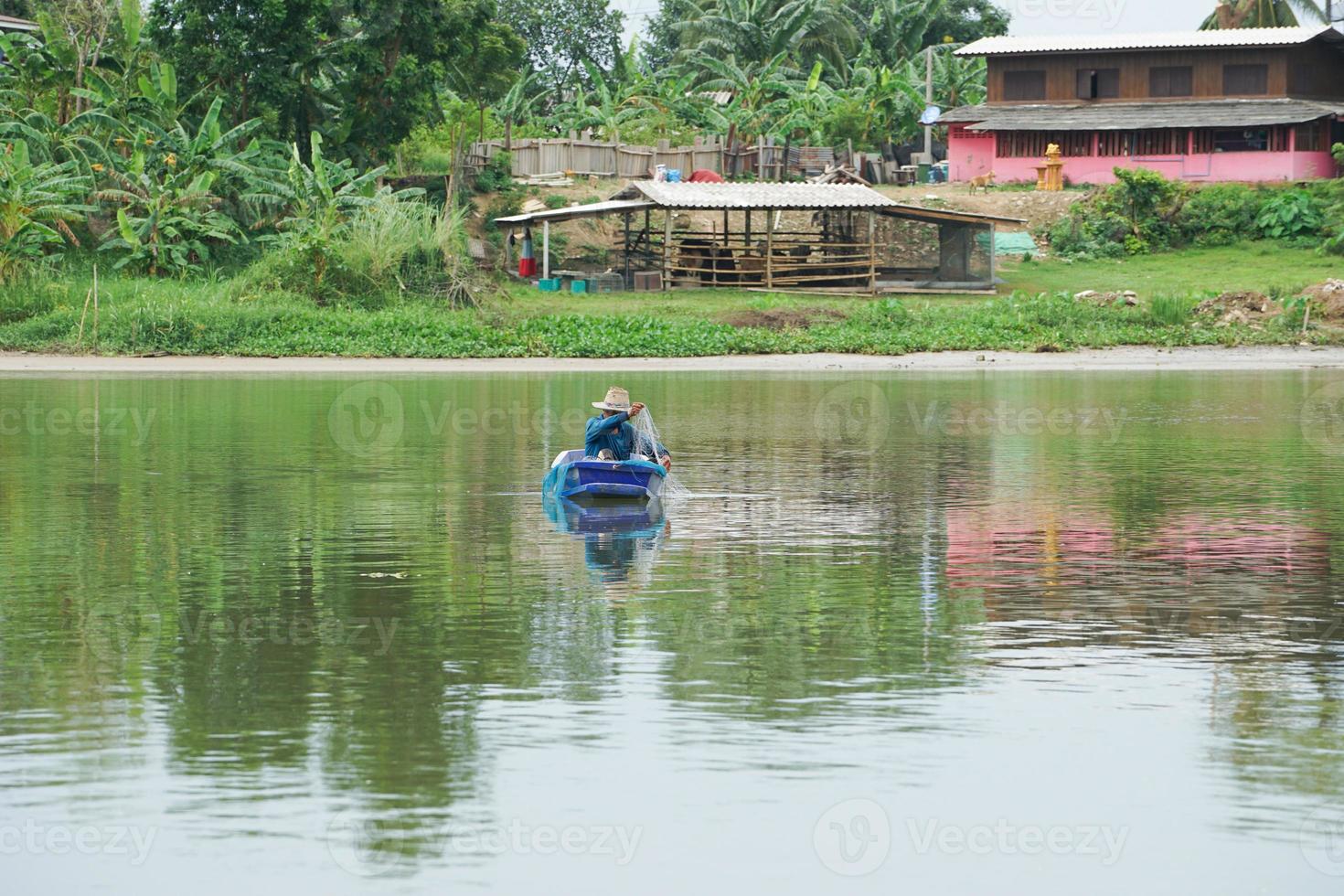 ensam man sitter i båten och samlar fisken från nätet foto
