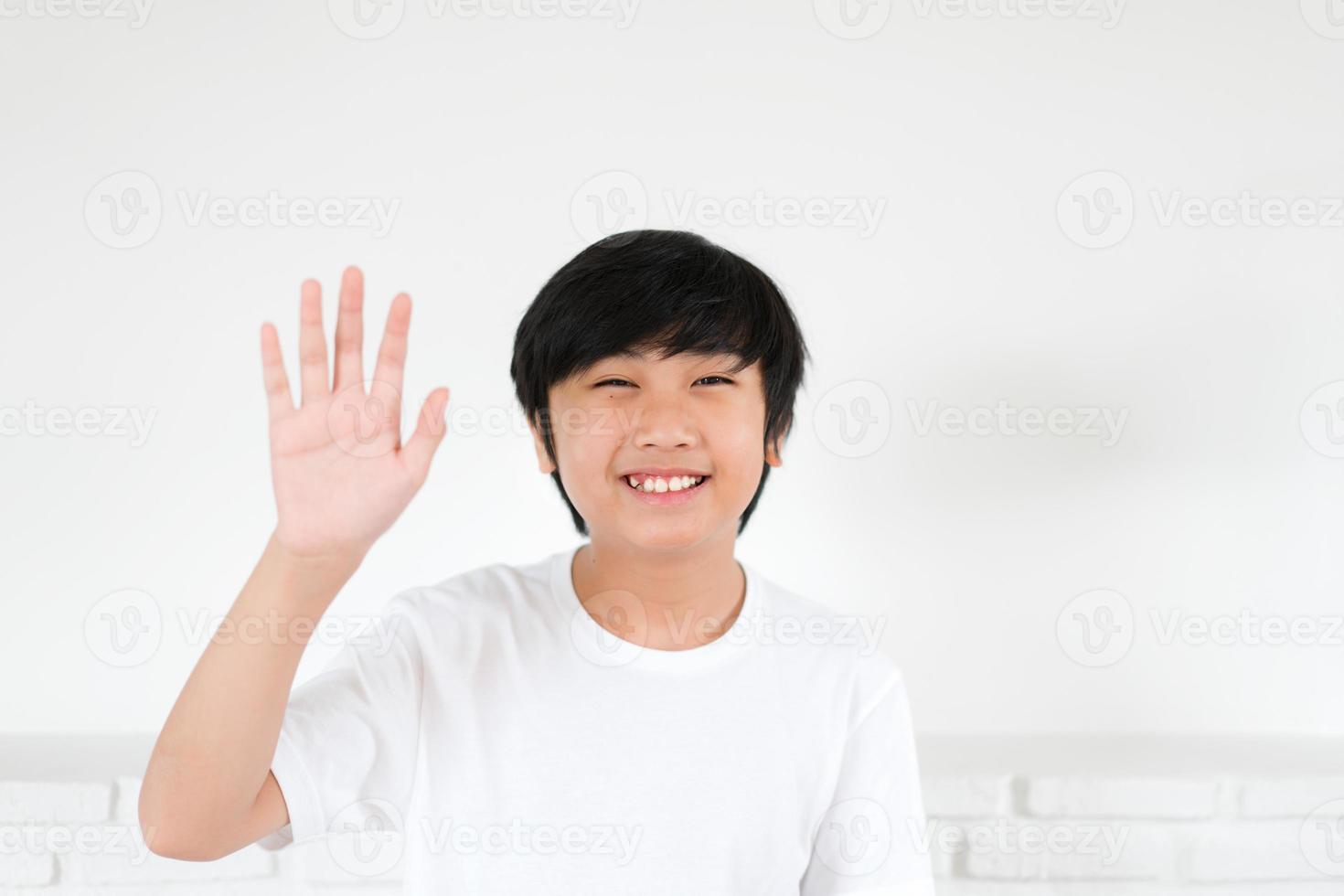 porträtt asiatisk pojke viftande hand för hälsning på vit bakgrund foto