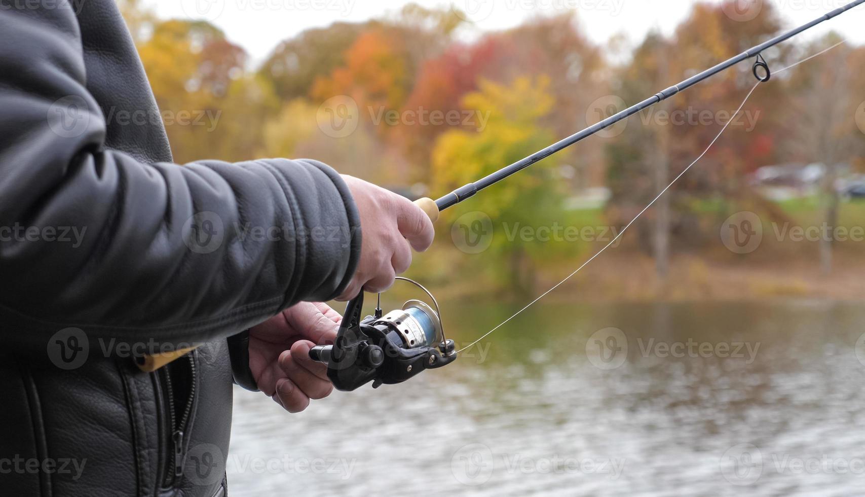 man som håller en fisk och spö vid sjön under hösten foto