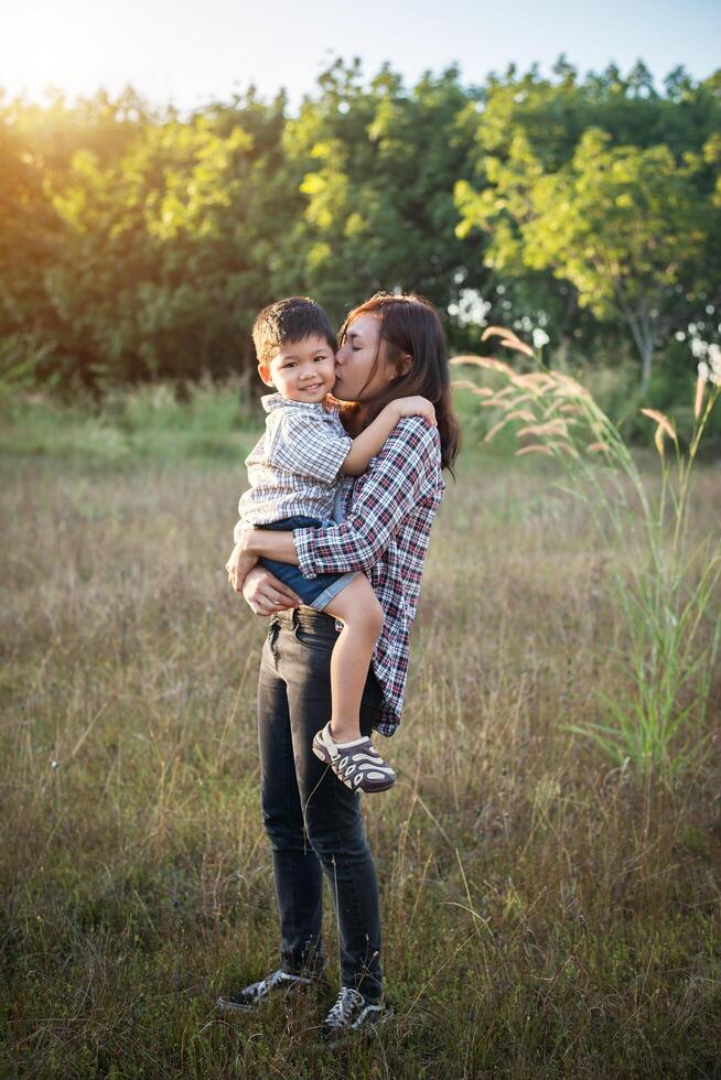 mamma kramar sin lilla pojke. familj gå i fältet. utomhus. foto