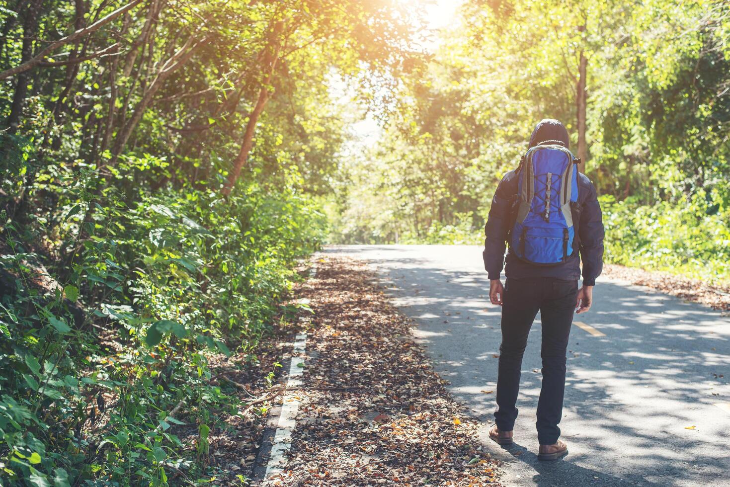 baksidan av vandringsmannen som går på landsbygdsvägen. semester turism koncept. foto