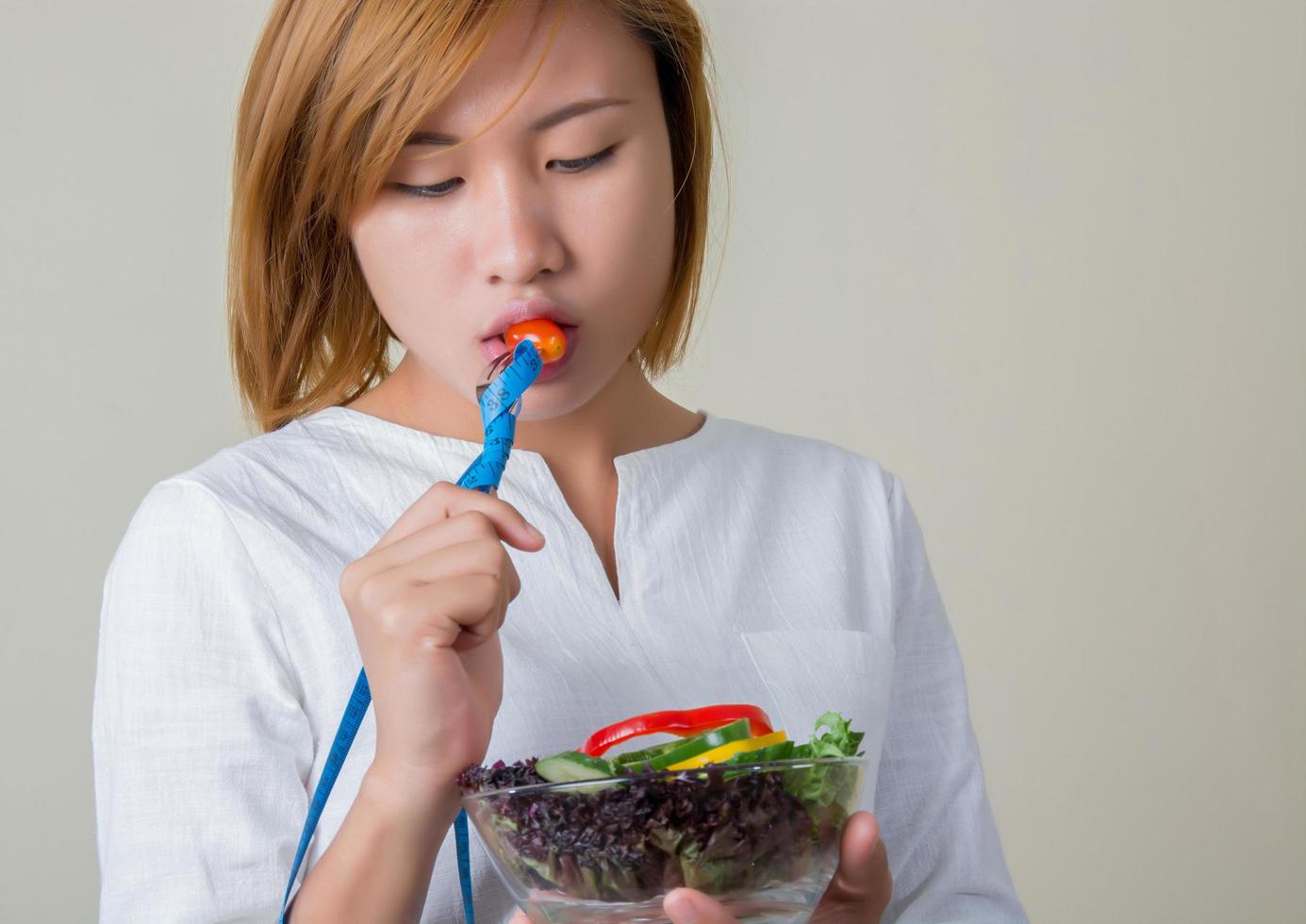 vacker kvinna som äter sallad med gaffelband insvept. foto