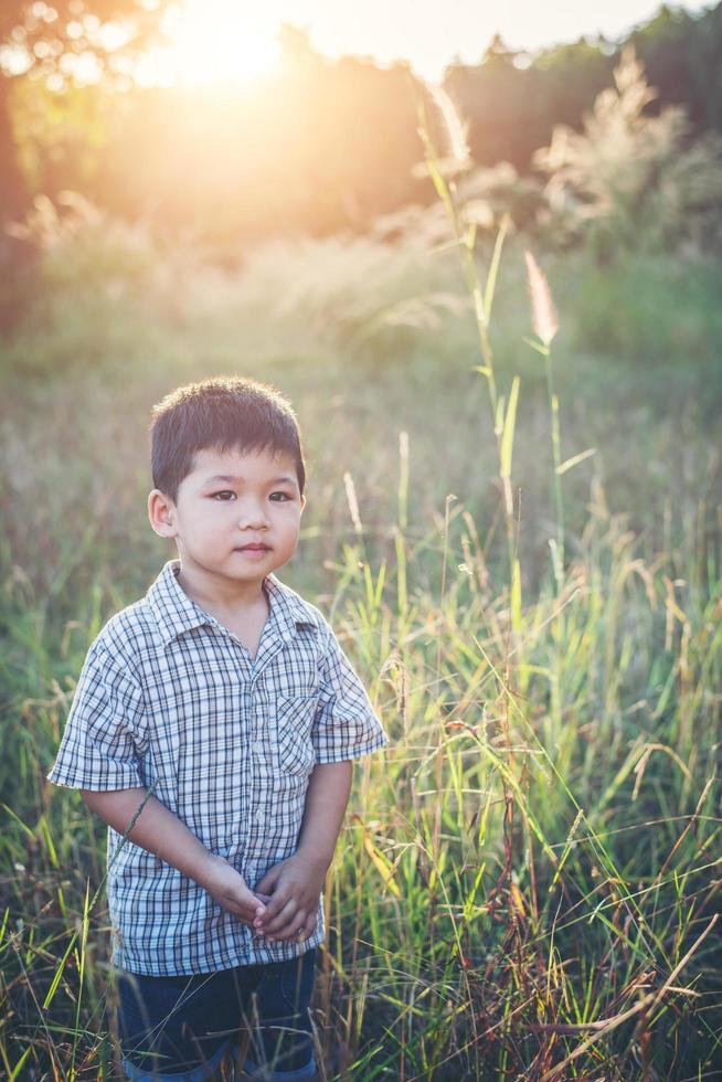 glad liten asiatisk pojke som leker utomhus. söt asiatisk. pojke på fältet. foto