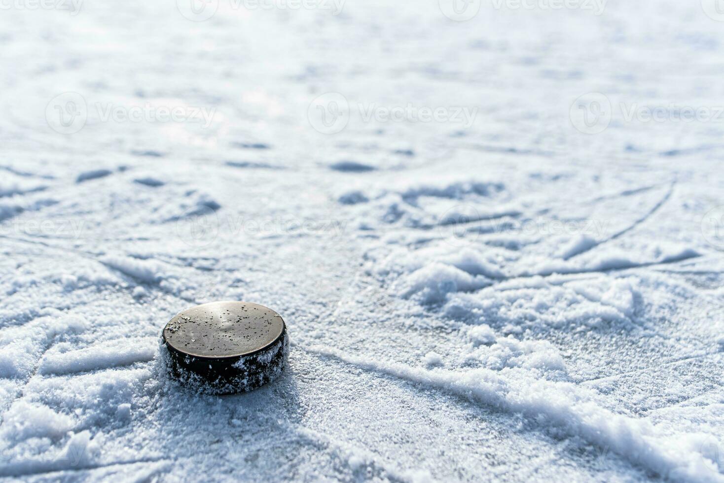 svart hockey puck lögner på is på stadion foto