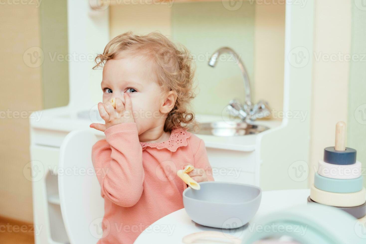 Lycklig liten flicka äter pasta i dagis foto