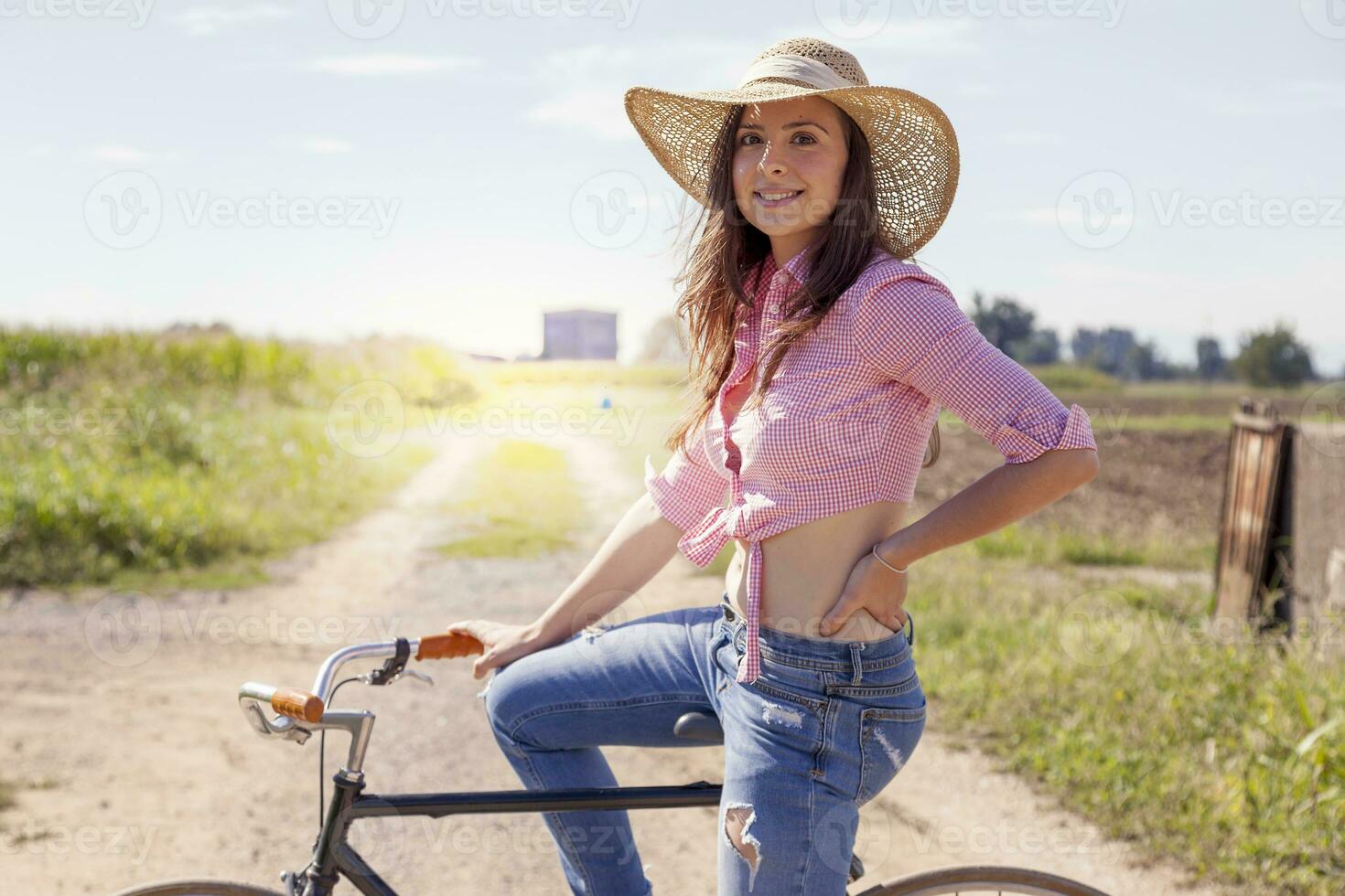 Söt ung kvinna på cykel i en Land väg foto