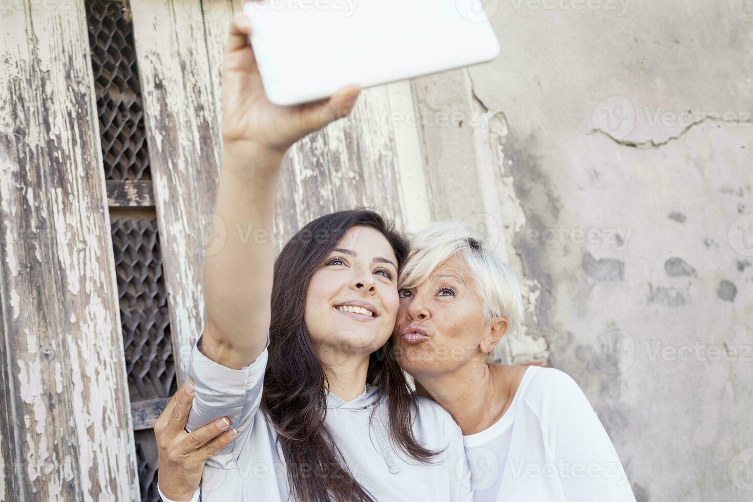 mor och vuxen dotter ta en selfie utomhus foto