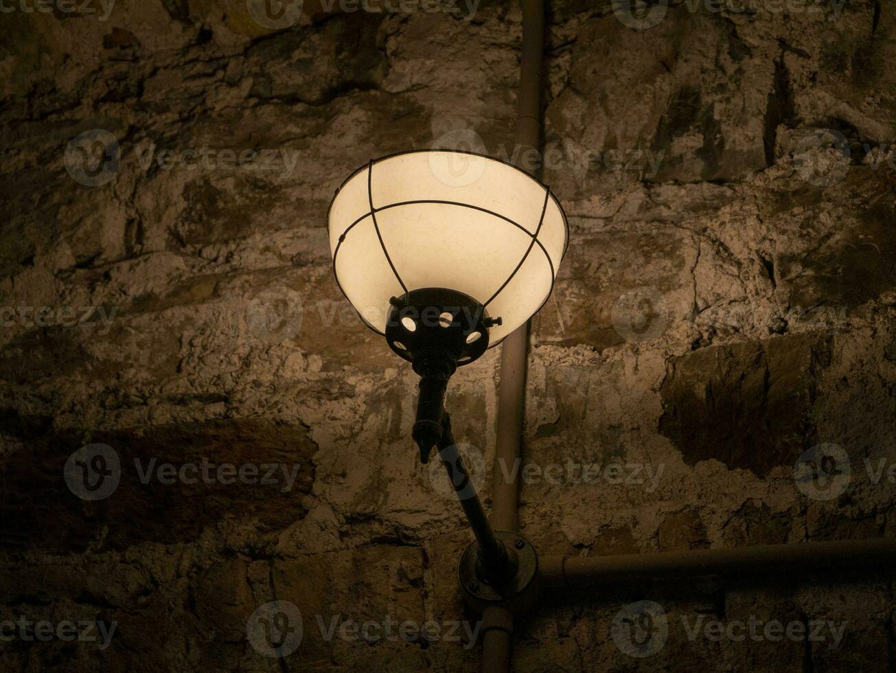 gammal gammal lampa på de vägg av en fängelse bakgrund, dyster ljus foto
