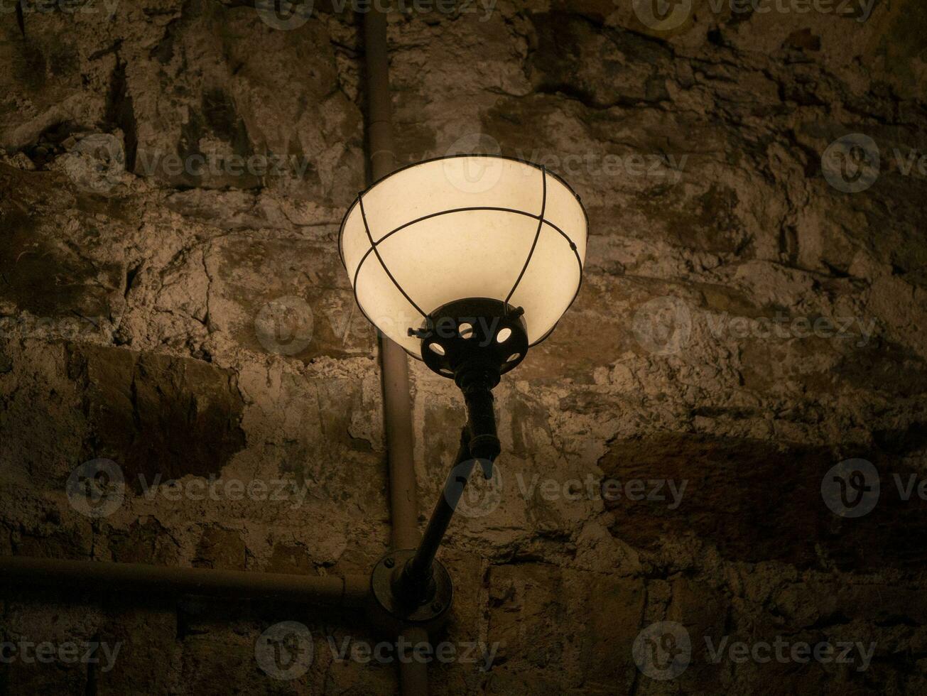 gammal gammal lampa på de vägg av en fängelse bakgrund, dyster ljus foto