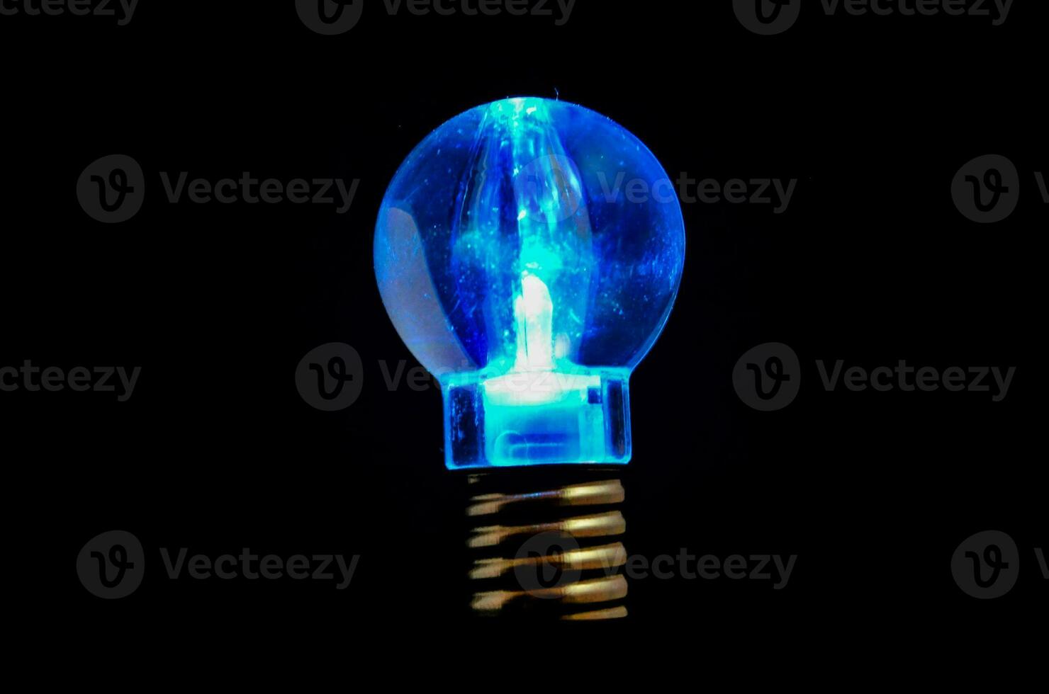 en blå ljus Glödlampa är belyst upp på en svart bakgrund foto
