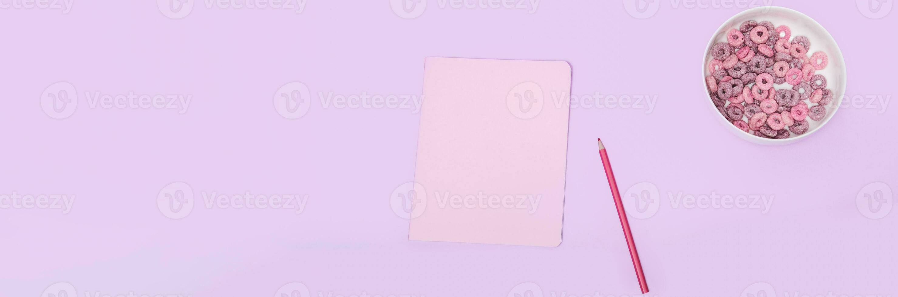 baner rosa anteckningsbok med en penna och majs flingor på en lila bakgrund, topp se. frukost flickor skol foto