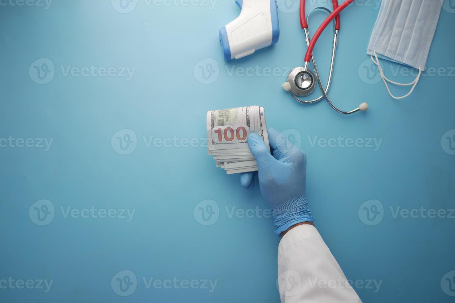 läkare lämnar in handskar som håller oss dollar kontanter på blå bakgrund foto